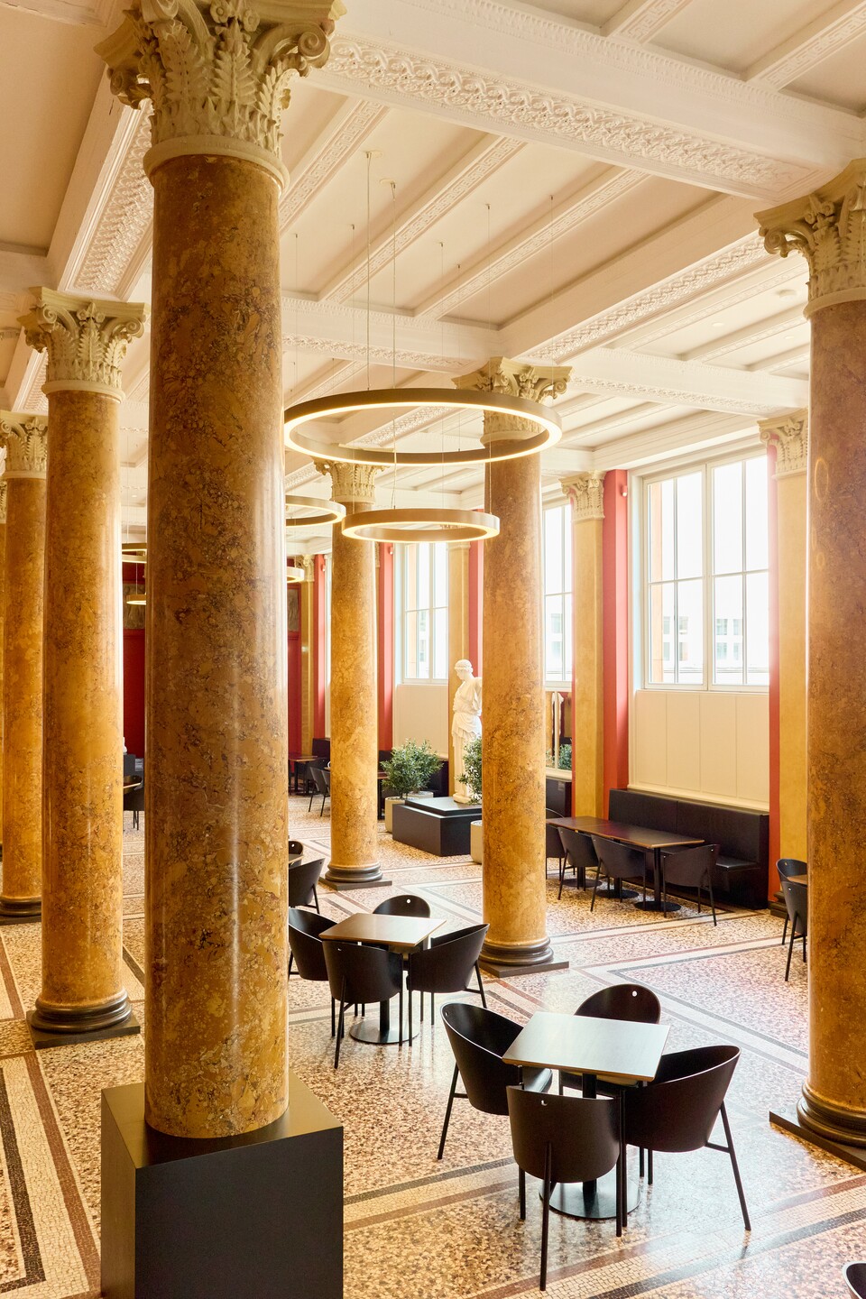 Eleganter Café-Innenraum mit Säulen, runden Tischen und schwarzen Stühlen